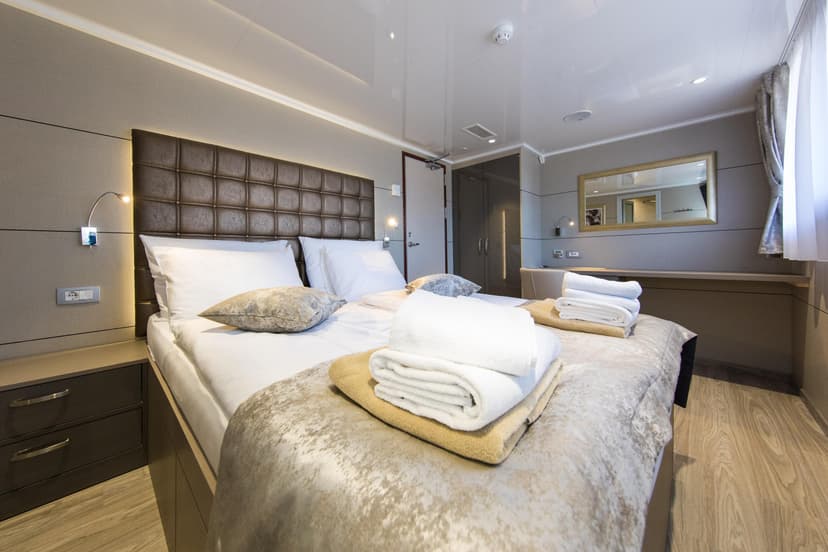 Modern cabin main deck stateroom with double bed and neatly folded towels