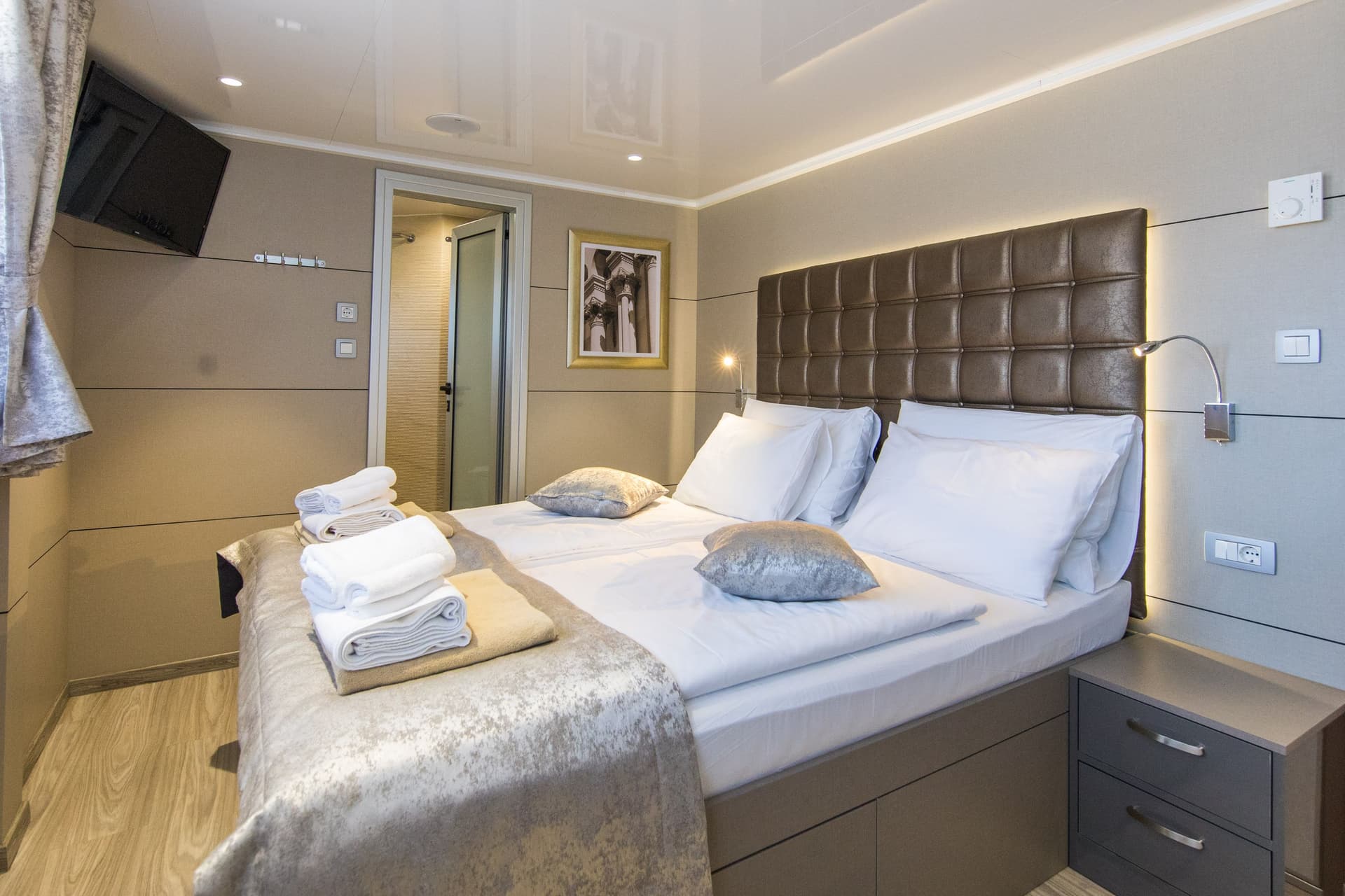 Modern cabin bedroom with tufted headboard, folded towels on bed, and attached bathroom doorway