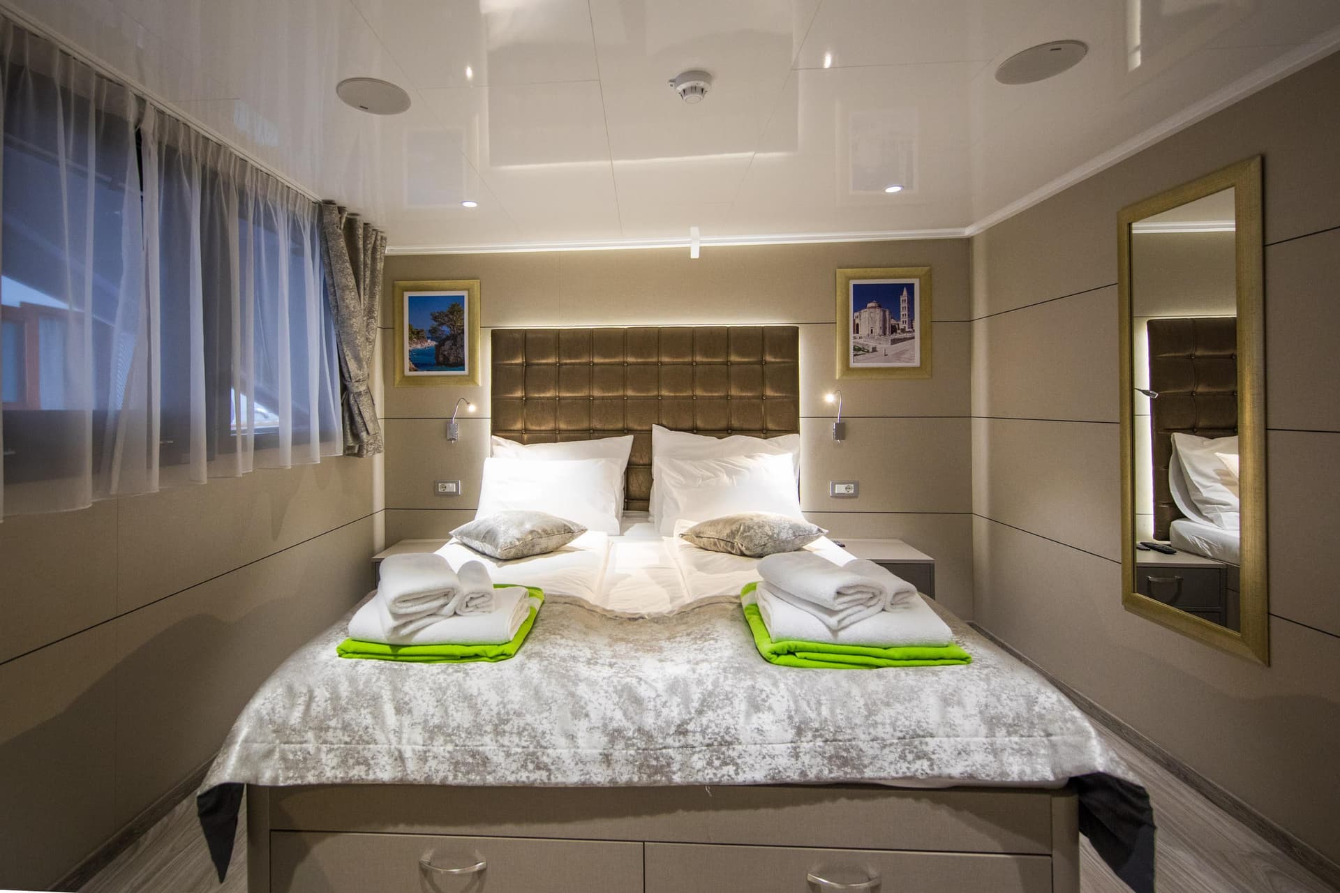 Modern cabin bedroom with double bed, white linens, folded towels, and framed wall art