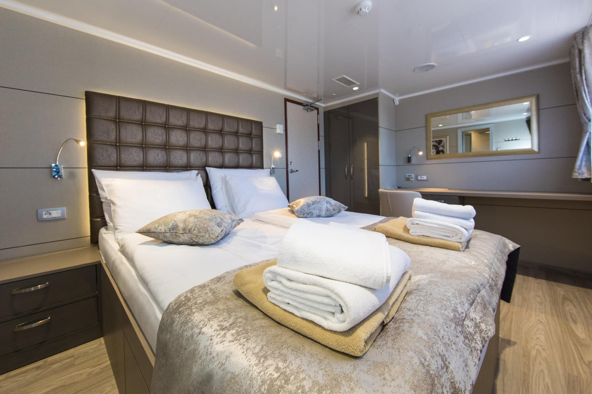 Modern cruise ship cabin bedroom with made beds and folded towels