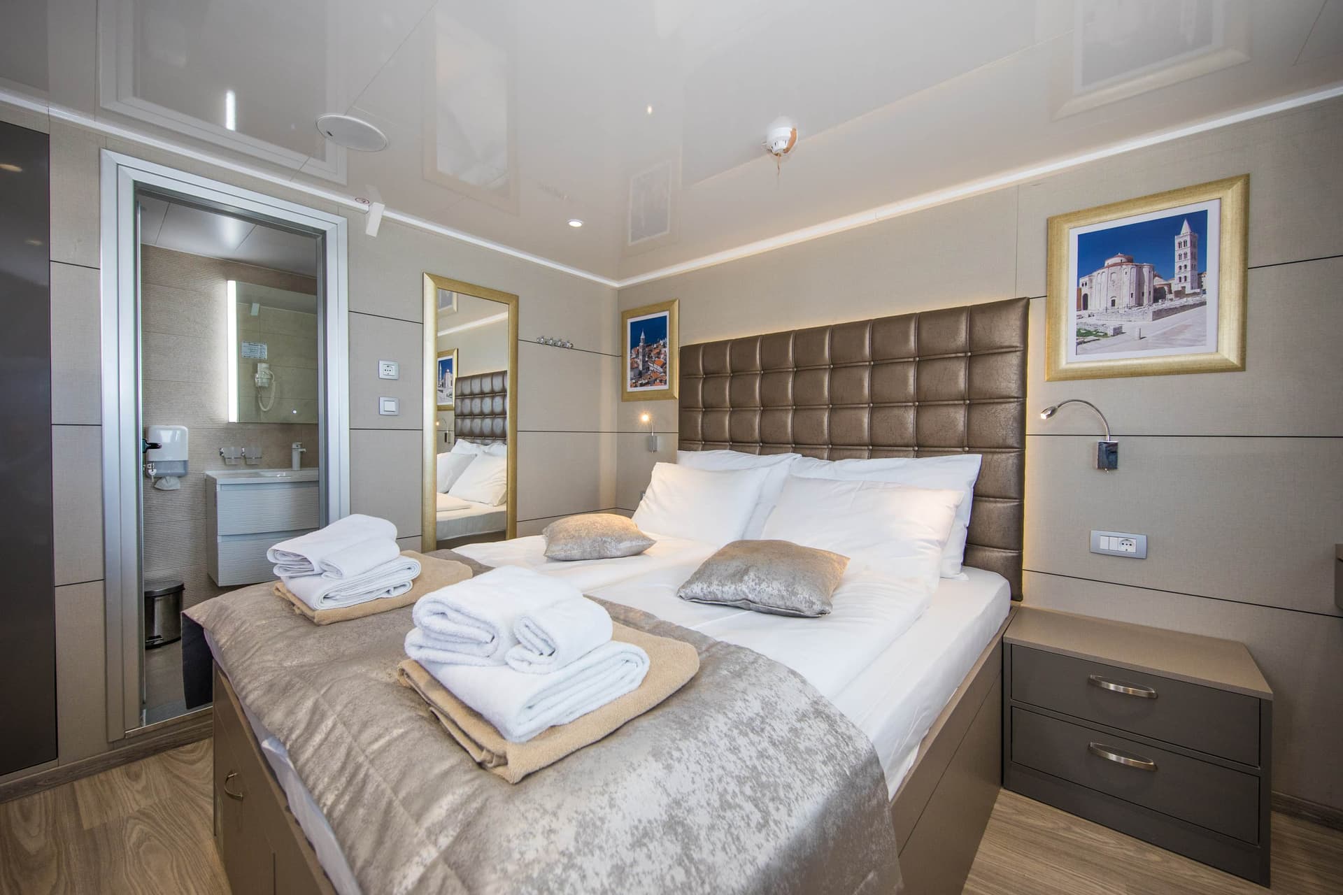 Modern standard cabin interior with double bed and adjoining bathroom on a vessel