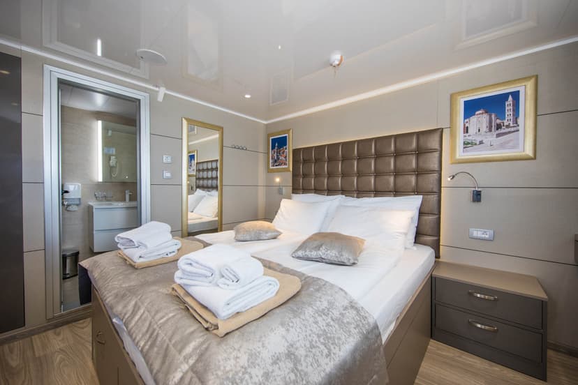 Modern standard cabin interior with double bed and adjoining bathroom on a vessel