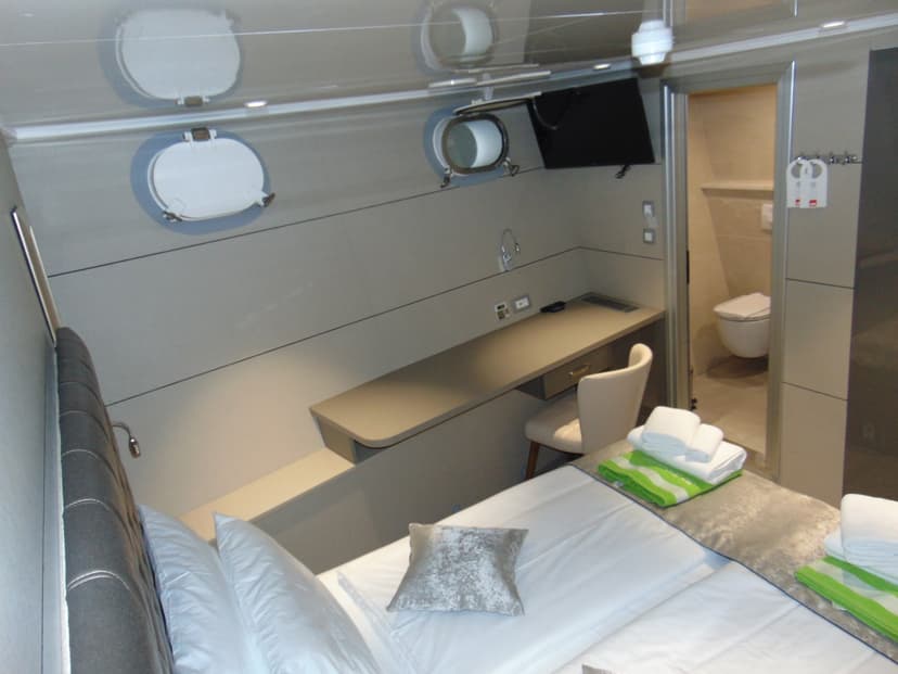 Modern boat cabin interior with bed, desk, and attached bathroom