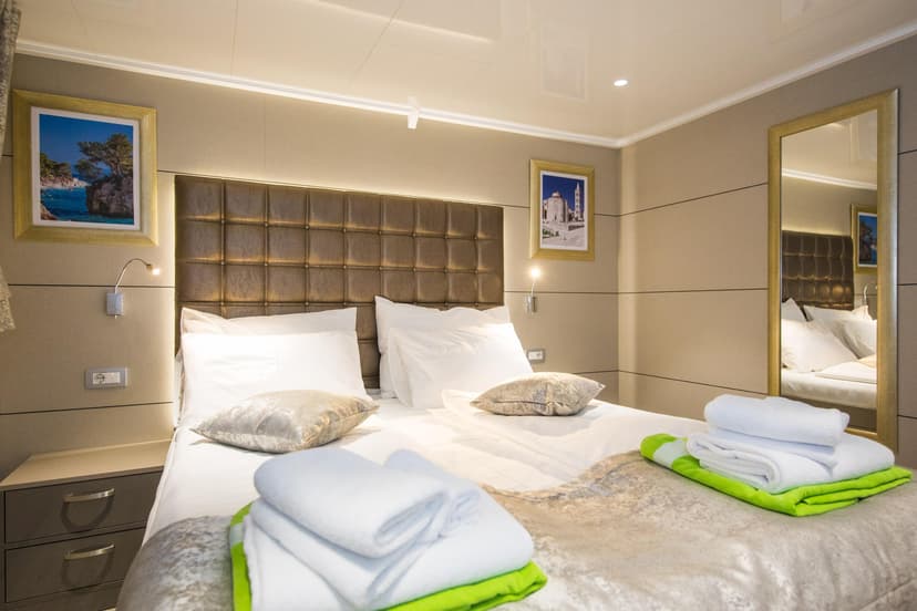 Standard cabin bedroom with double bed, white linens, and folded towels