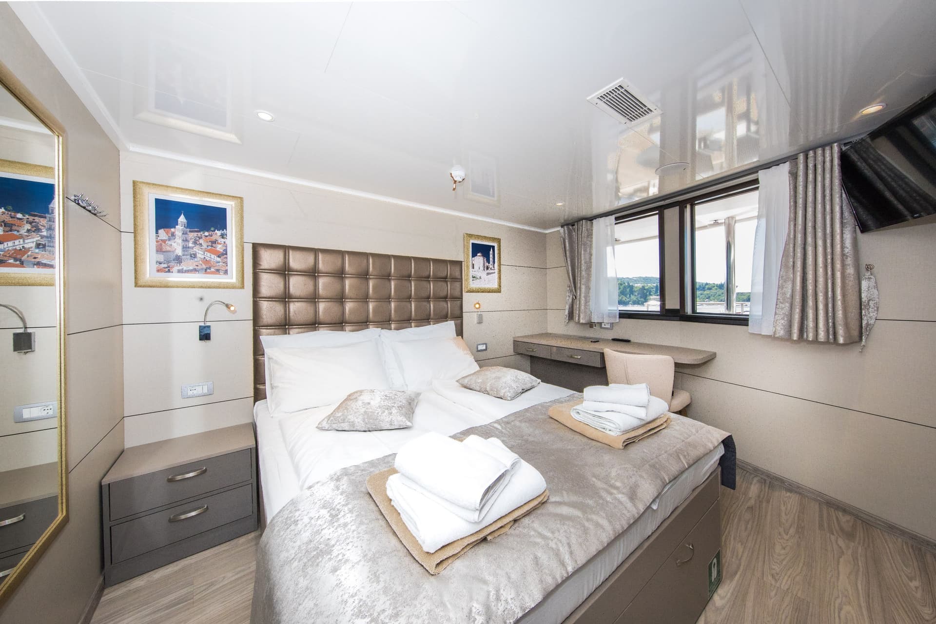 VIP cabin bedroom with a double bed, white linens, towels, and a window view