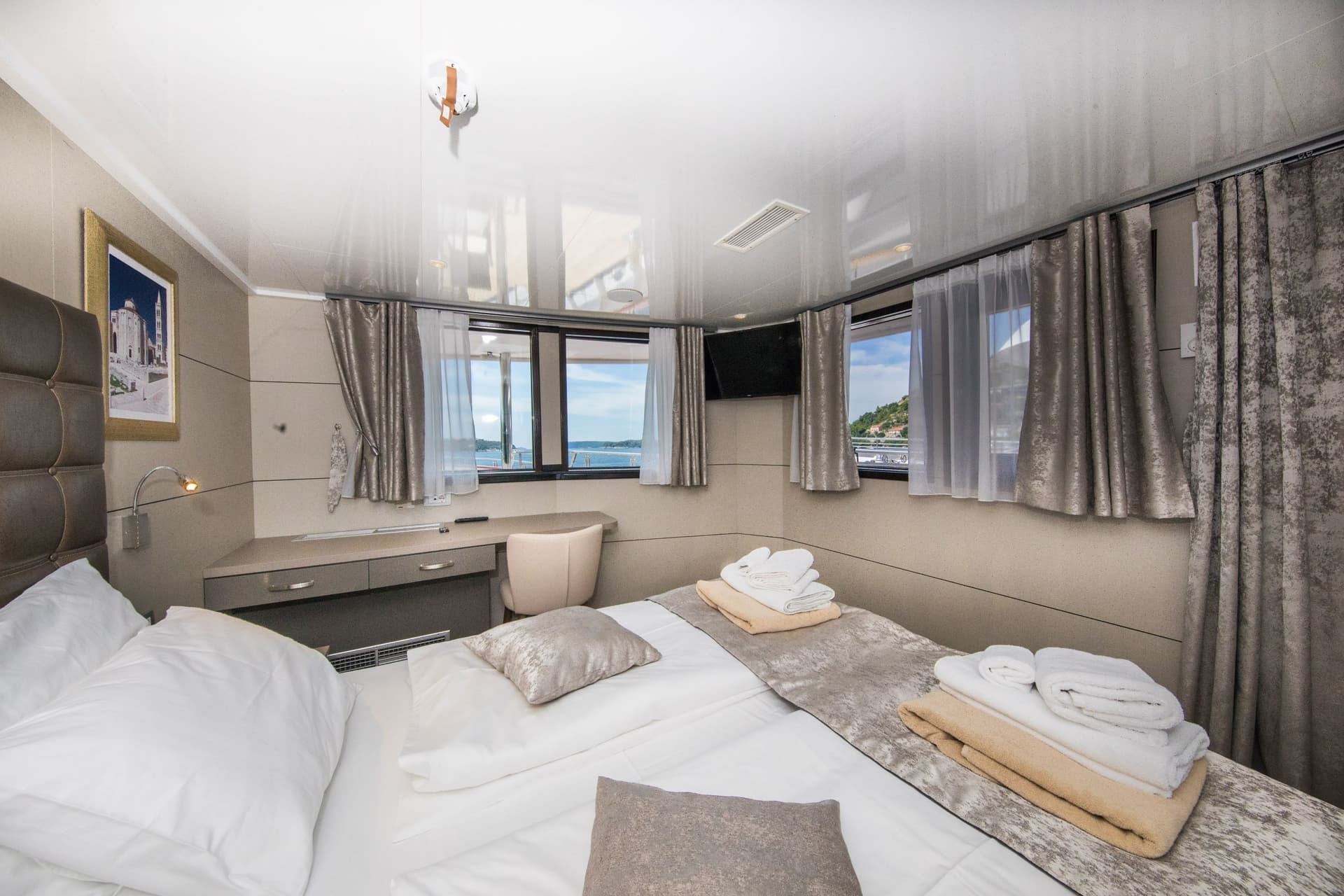Luxury VIP cabin interior on yacht with bed, desk, and large windows overlooking water