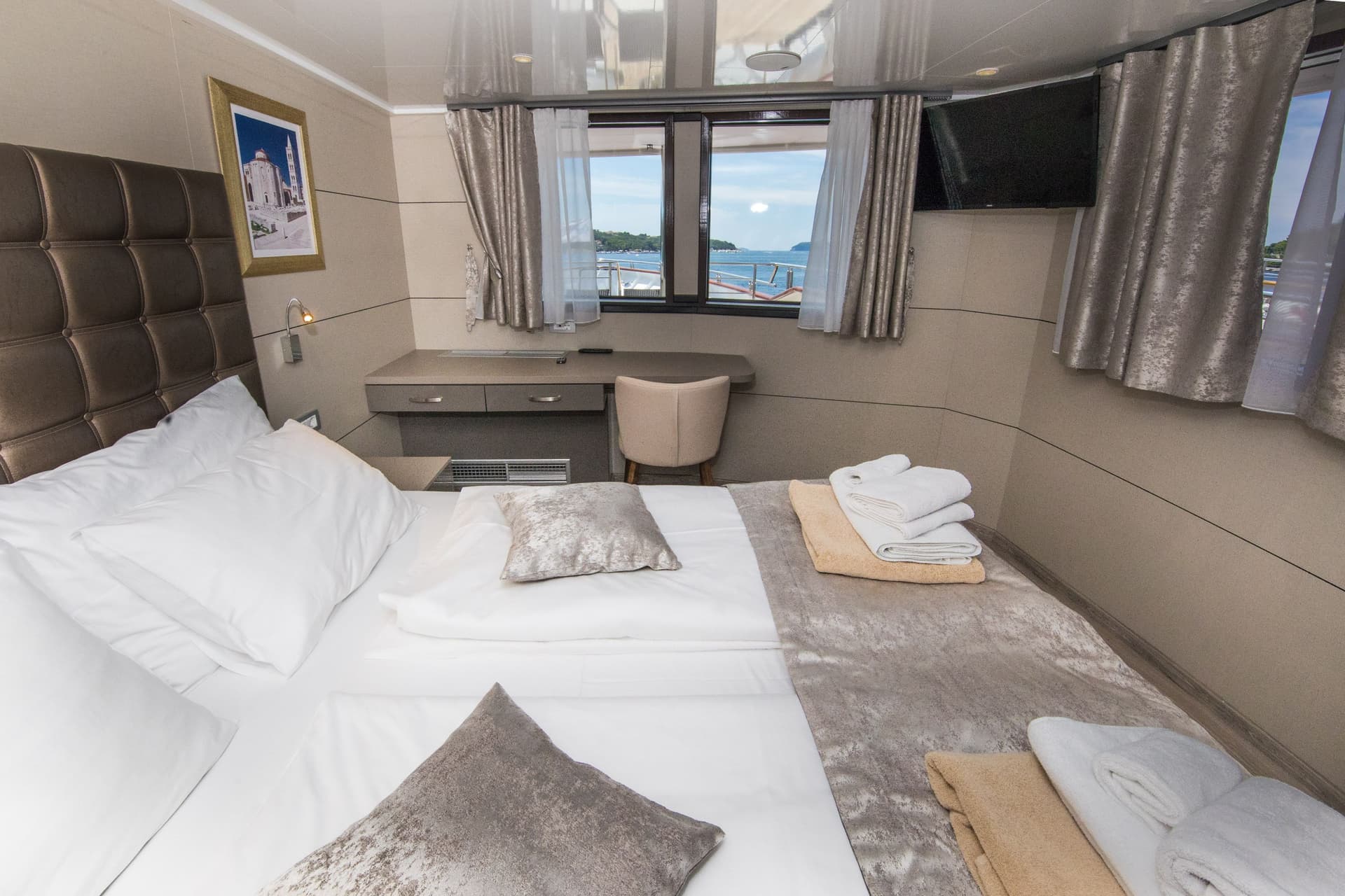 VIP cabin interior on boat with bed, desk, and window overlooking sea