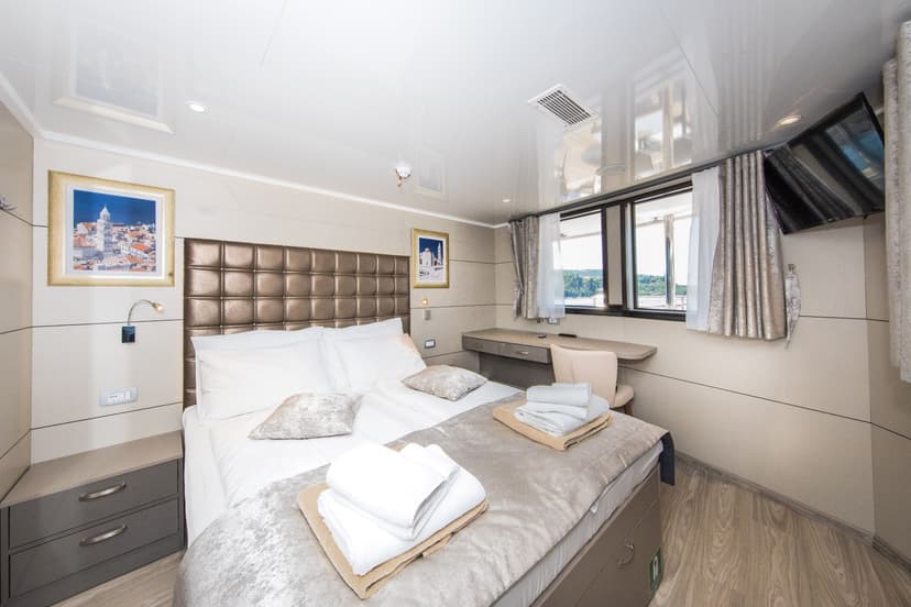 VIP cabin bedroom with a double bed, white linens, folded towels, and framed artwork on the walls