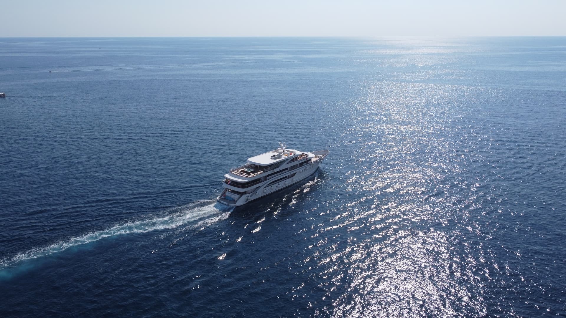 Yacht cruising on sparkling open sea water from aerial view