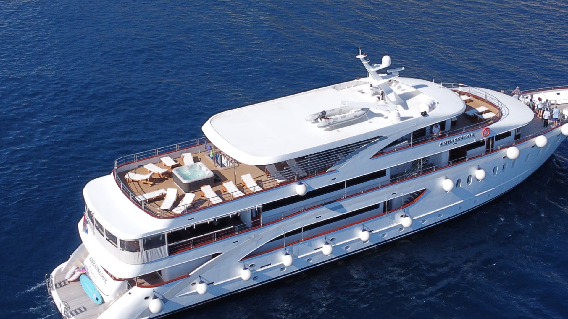 White yacht cruising on blue sea water with sun loungers on deck
