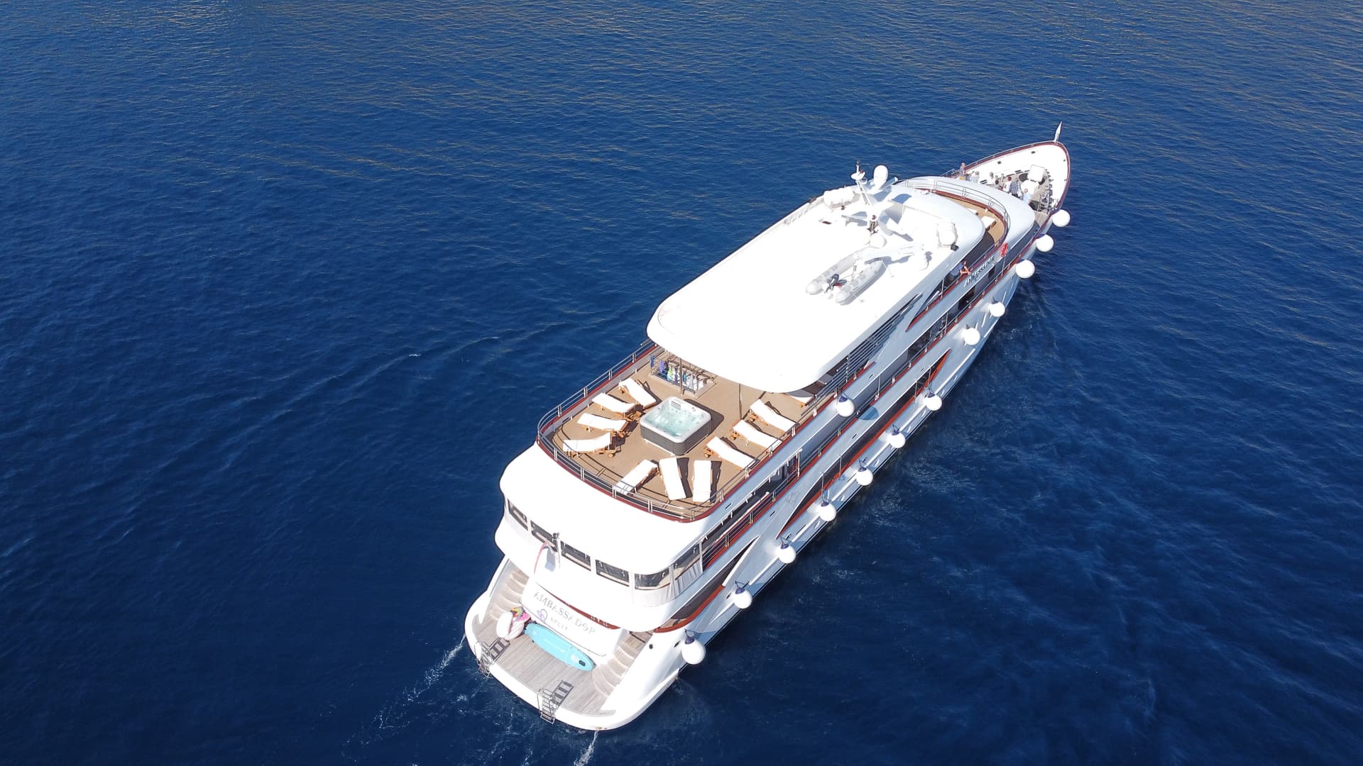 Aerial view of a white cruise yacht sailing on blue sea water
