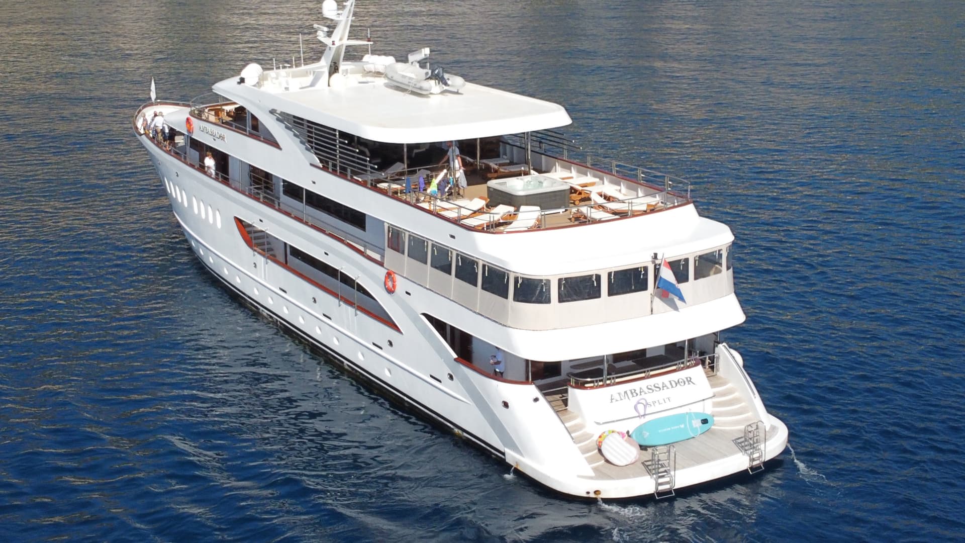 Large white yacht on blue sea water with sun deck and hot tub