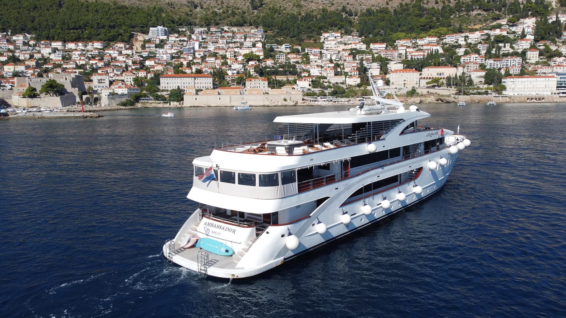 Ambassador yacht on coastal waters with town in background