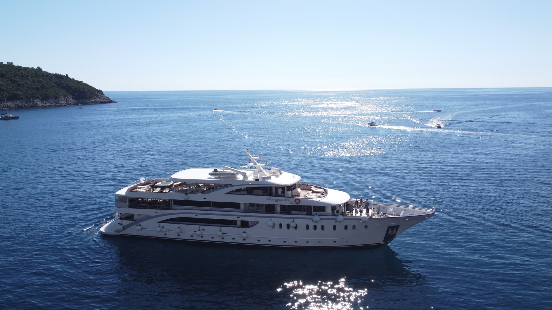 Large white yacht on sparkling blue sea with distant coastline