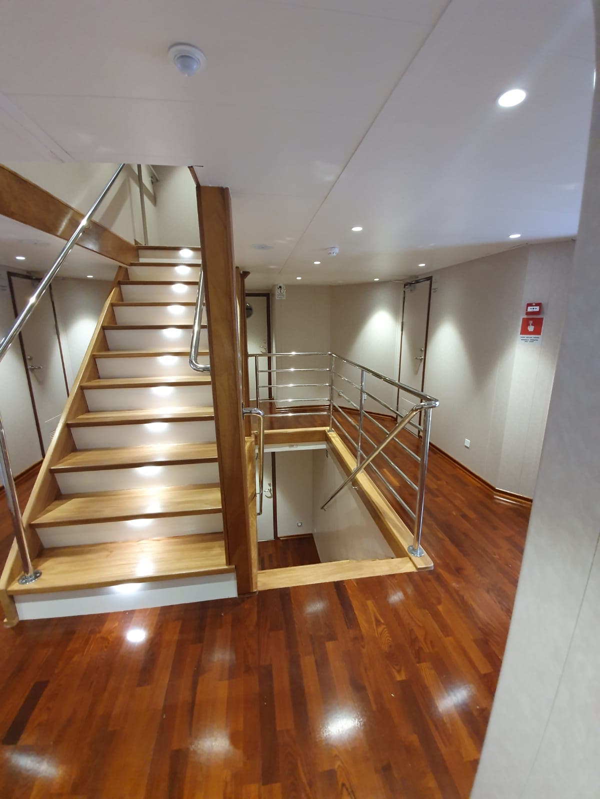Wooden staircase with integrated lighting and metal railings connecting levels inside a vessel