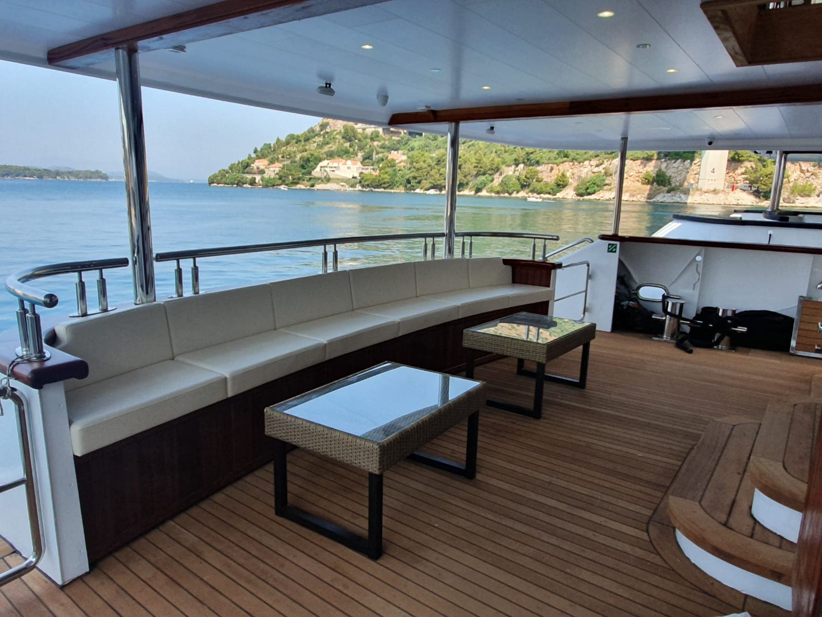 Yacht deck seating area with wooden flooring and coastal view