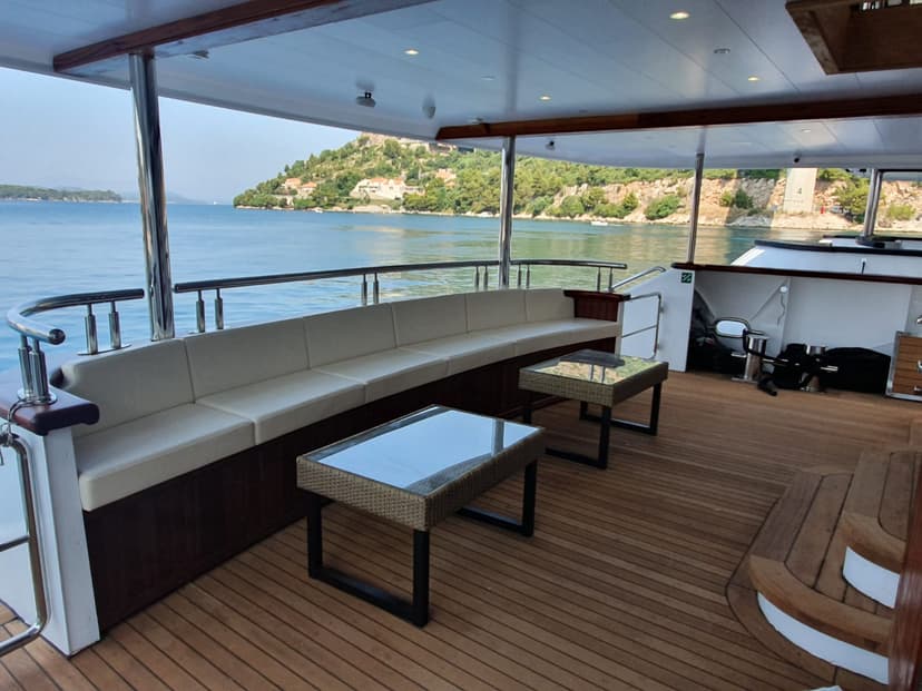Yacht deck seating area with wooden flooring and coastal view