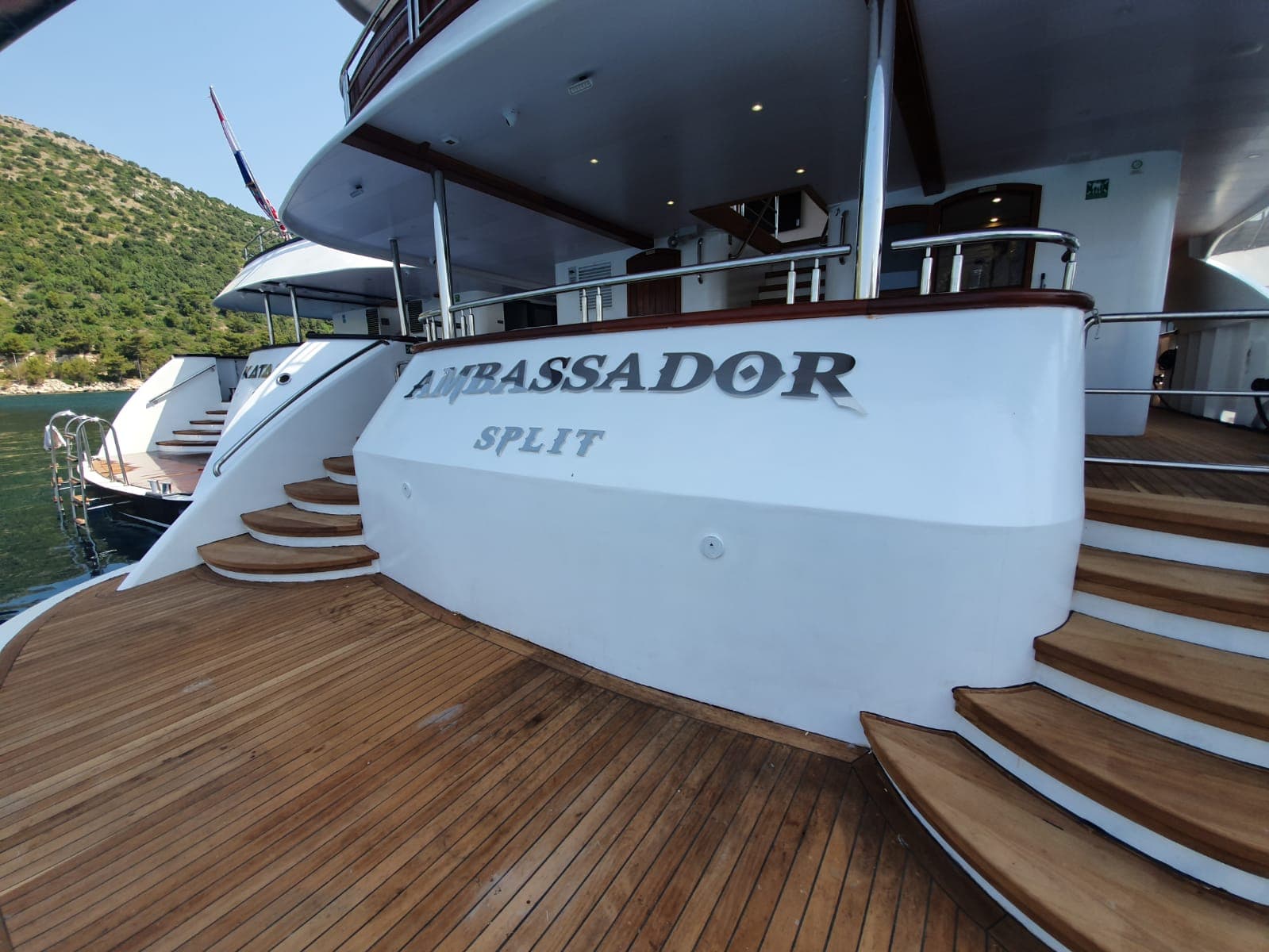 Yacht stern with wooden deck and stairs reading AMBASSADOR SPLIT