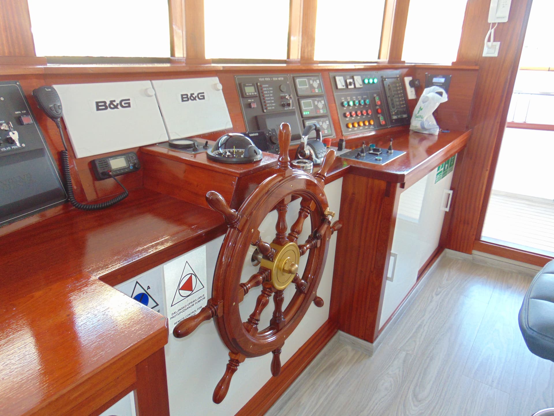 Wooden ship's wheel and control console inside boat wheelhouse