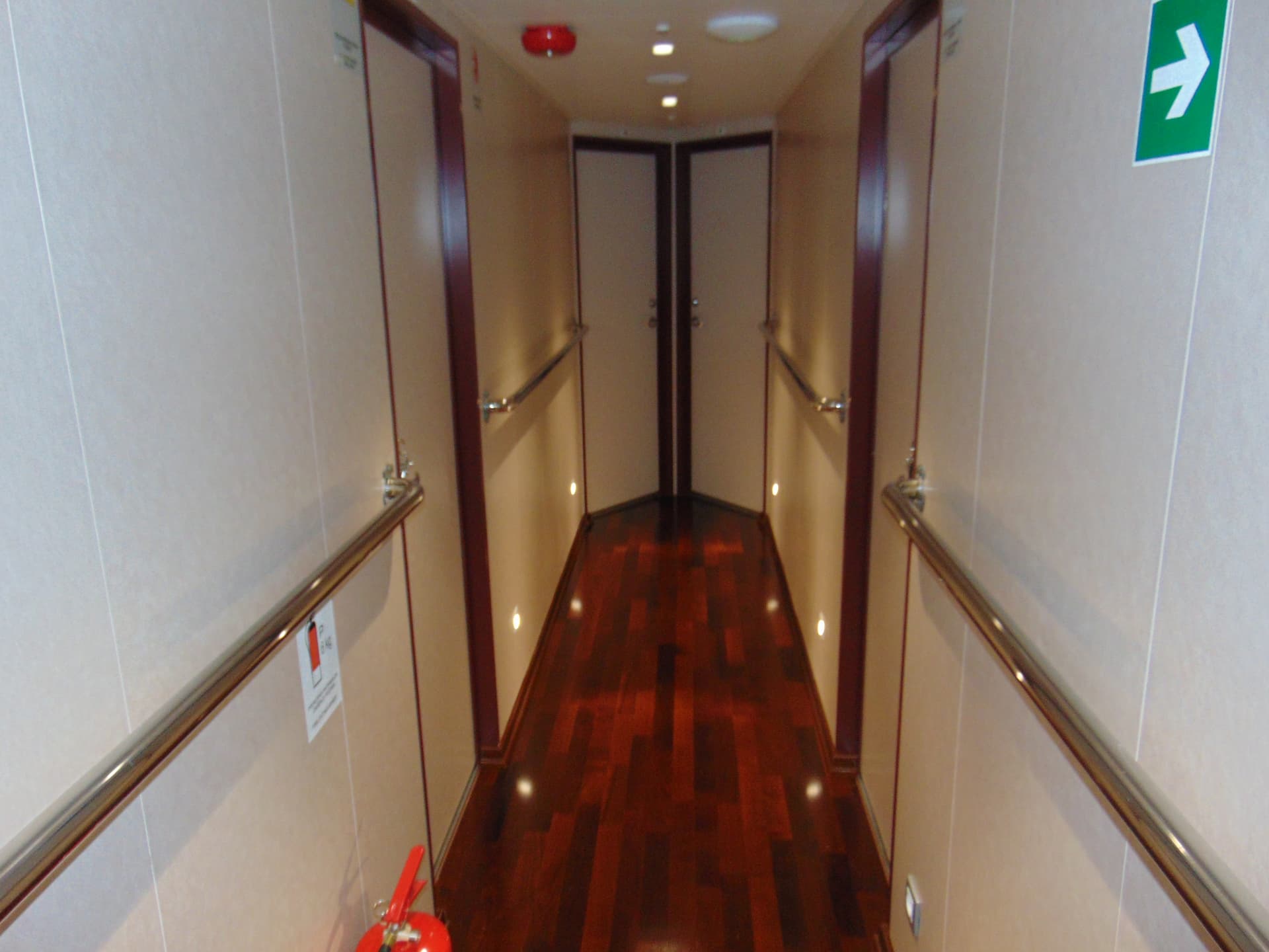 Ship hallway with wood flooring, handrails, and cabin doors
