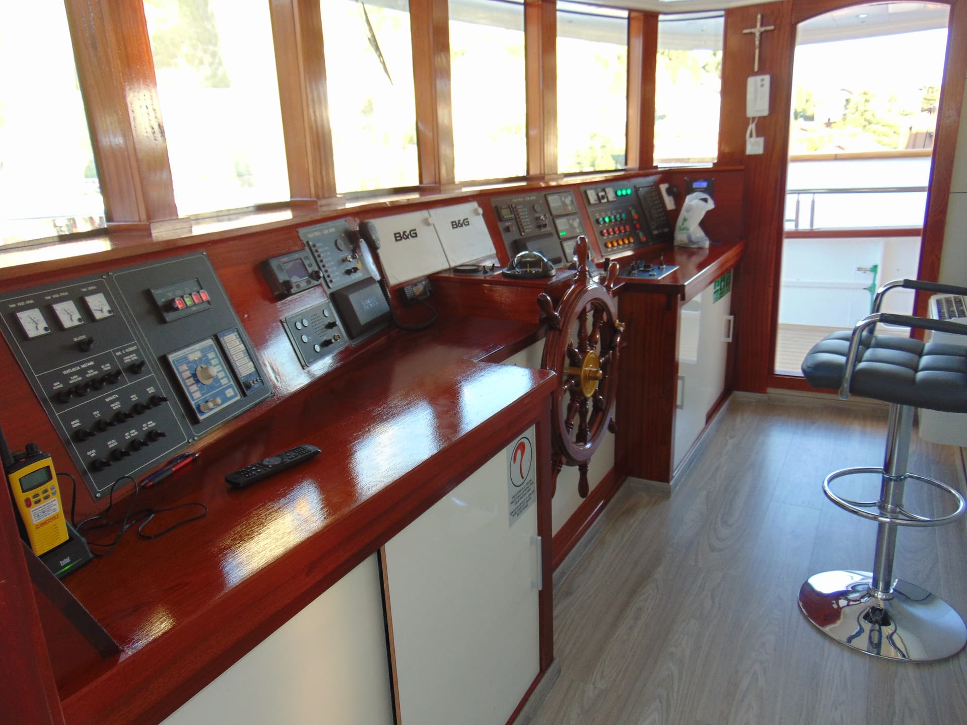 Boat wheelhouse interior with wooden dashboard, controls, and helm steering wheel