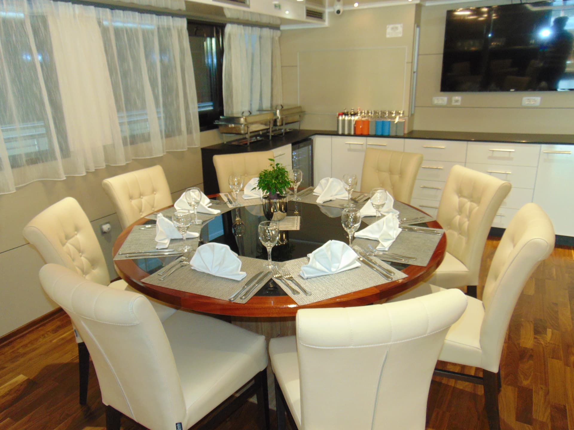 Round dining table with white upholstered chairs and place settings inside modern restaurant interior