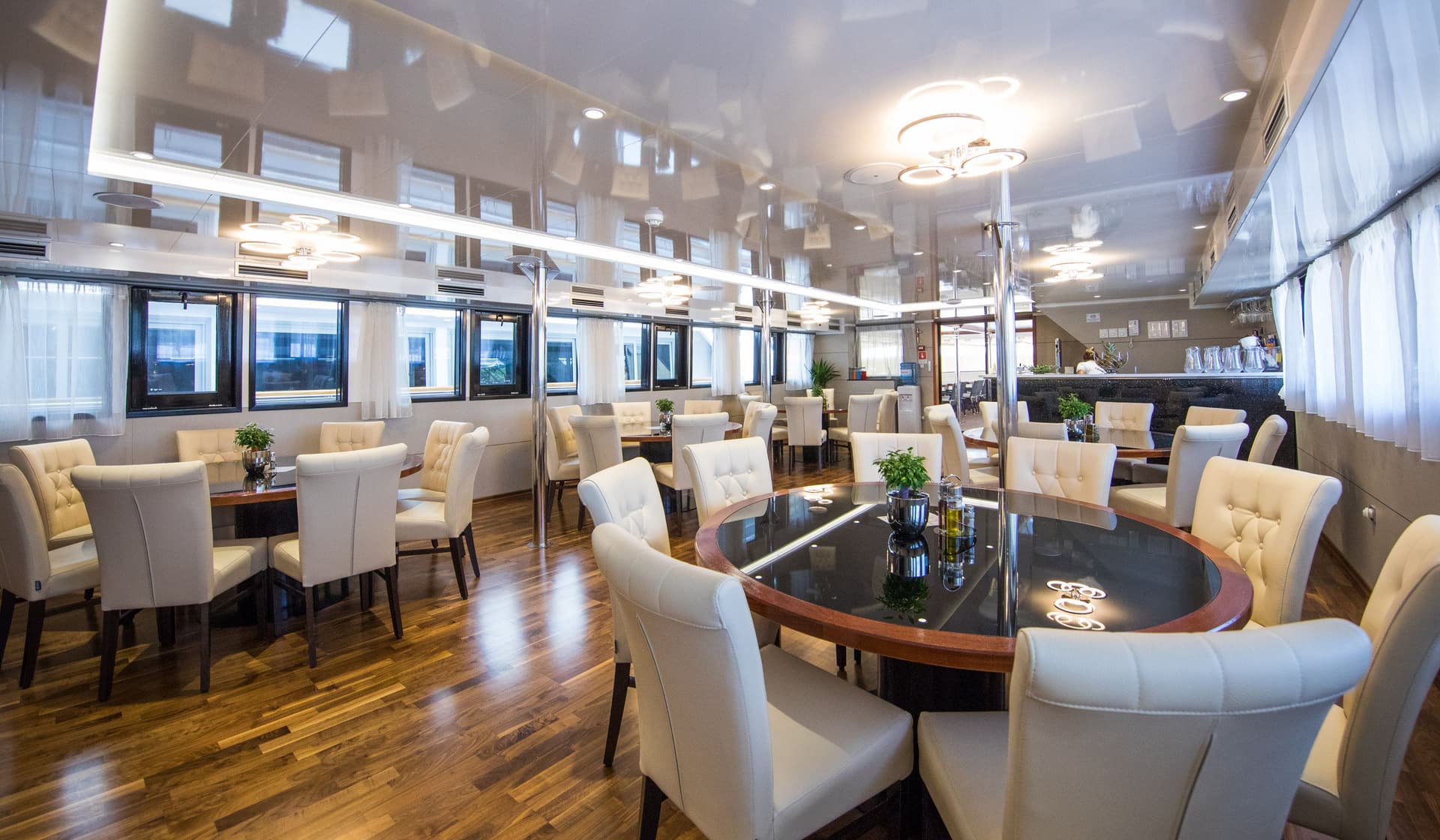 Modern restaurant interior with round tables, white tufted chairs, and polished wood floors