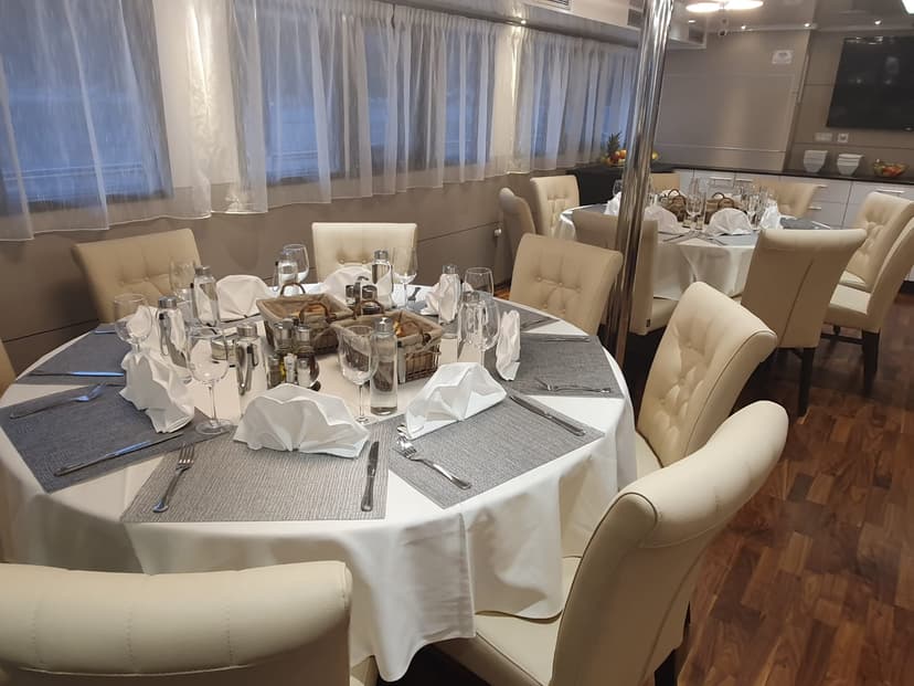 Restaurant dining room interior with round tables set with white tablecloths and beige chairs