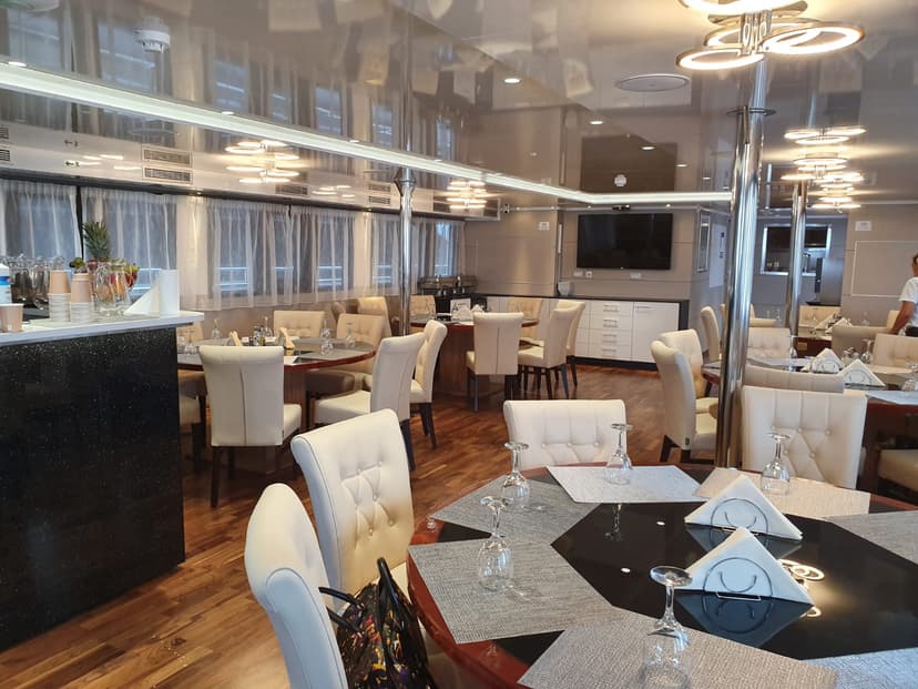 Modern restaurant interior with round dining tables, white chairs, and reflective ceiling