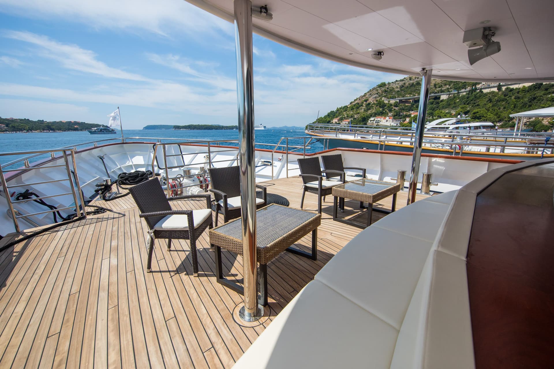 Sunlit yacht deck with outdoor seating and coastal views