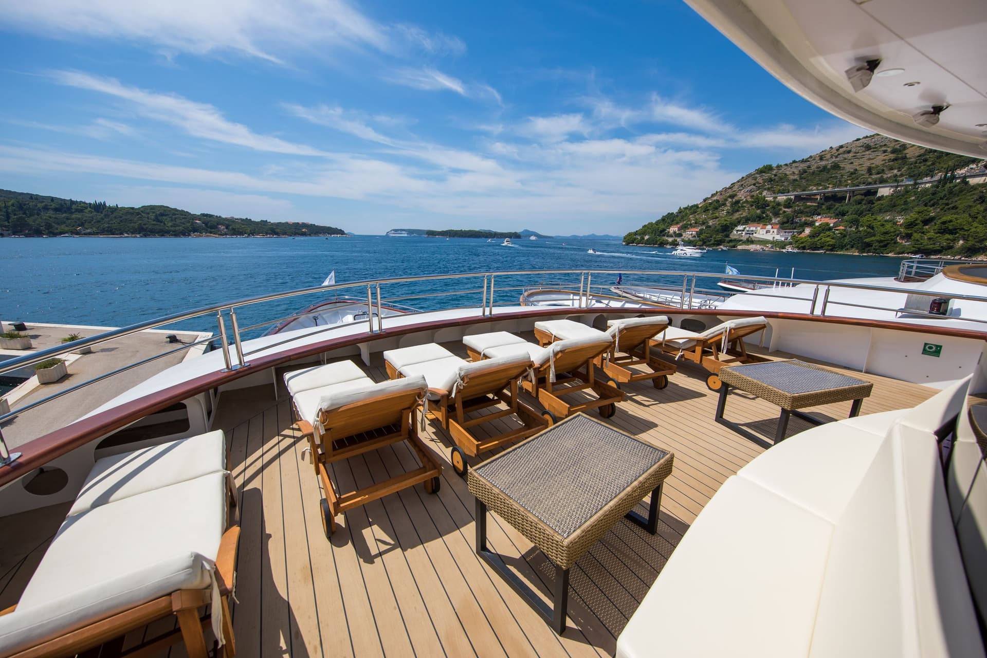 Sun loungers on a sunny yacht deck overlooking coastal waters