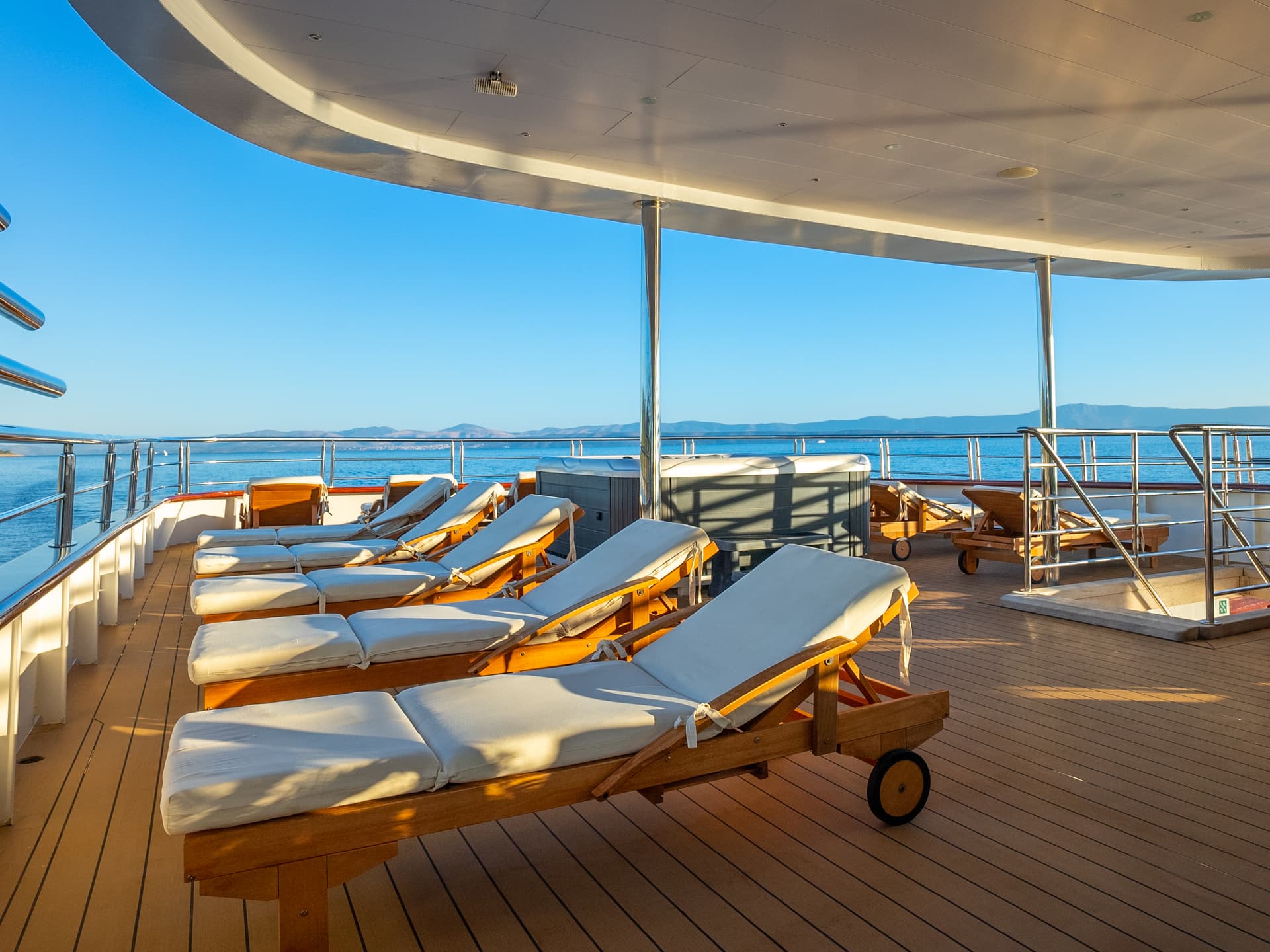 Sun loungers on wooden deck of cruise ship overlooking blue sea