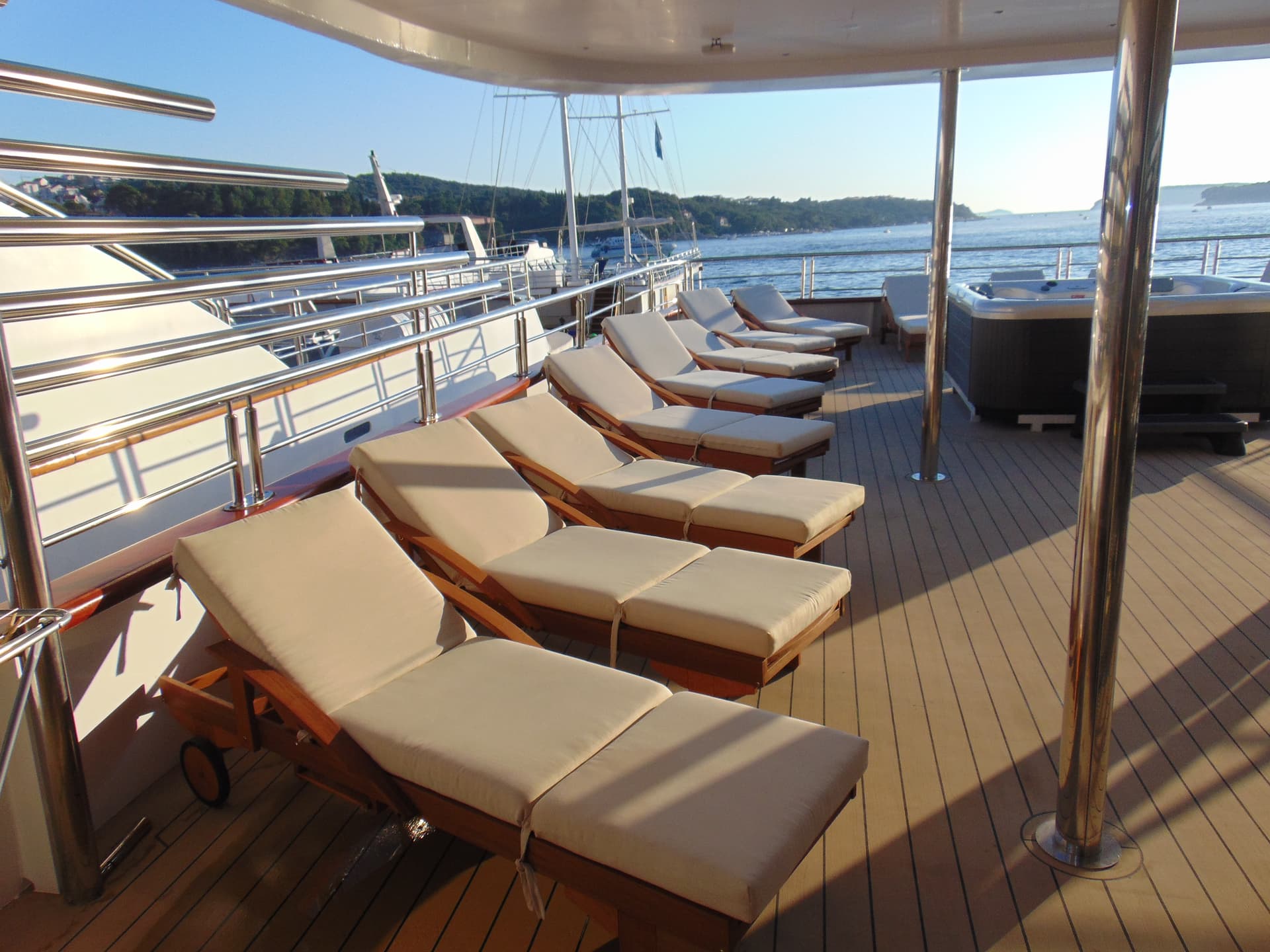 Sun deck with lounge chairs and hot tub on a yacht at sea
