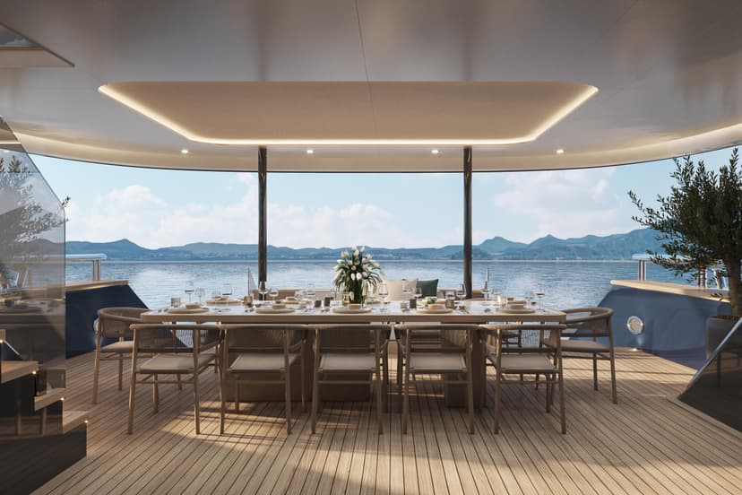 Luxury yacht dining area with set table overlooking calm coastal waters and distant hills
