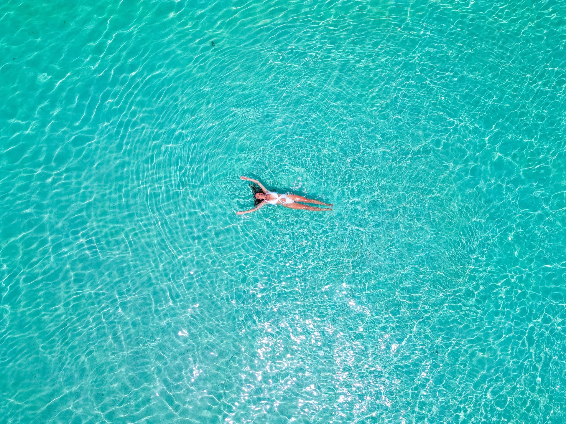 Woman floating on her back in clear turquoise water near Korcula Island.