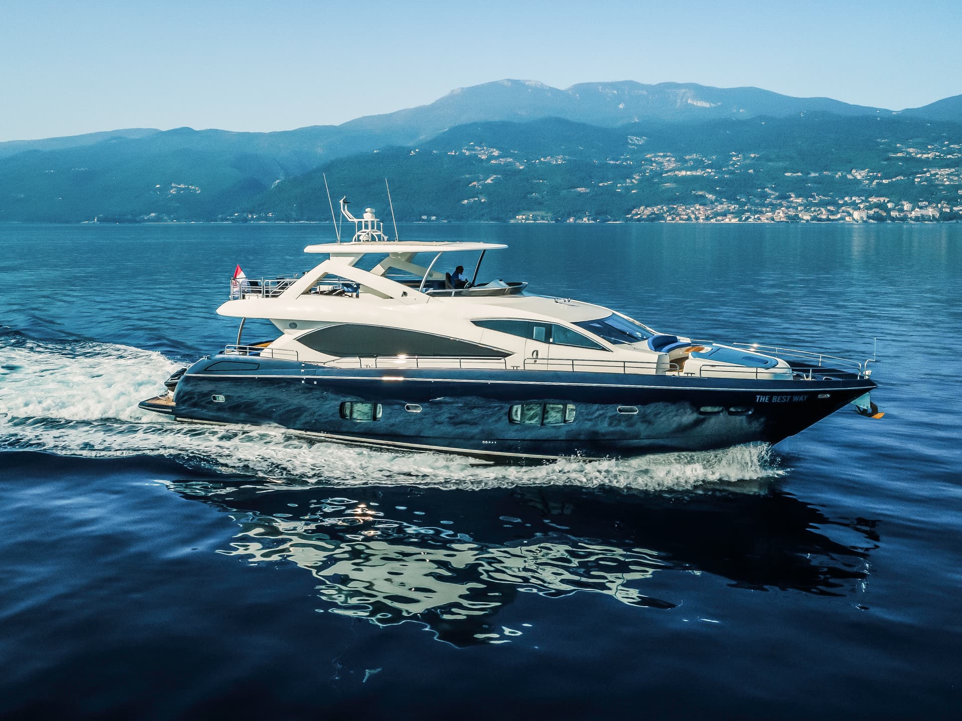 Motor yacht "The Best Way" speeding on deep blue water with mountains in background
