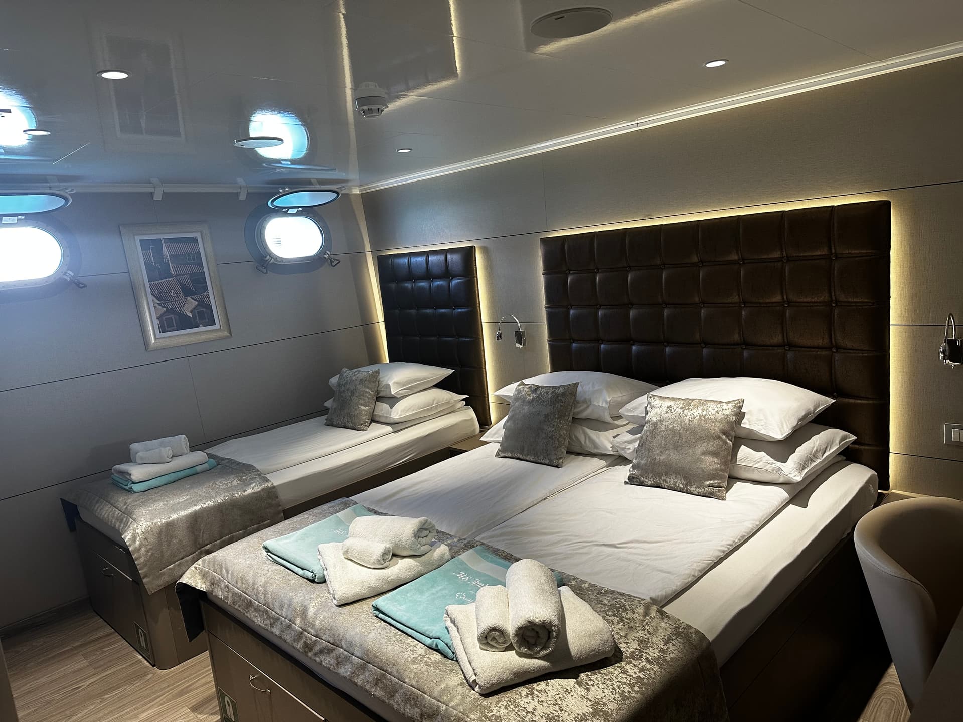 Triple hotel room with a double bed and a single bed with neatly folded towels