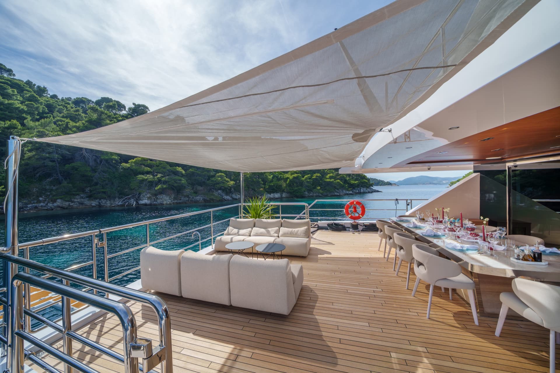 Luxury yacht deck with outdoor seating and dining area overlooking coastal waters