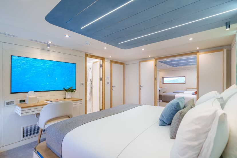Modern yacht interior stateroom with large bed, television, and connected cabin view
