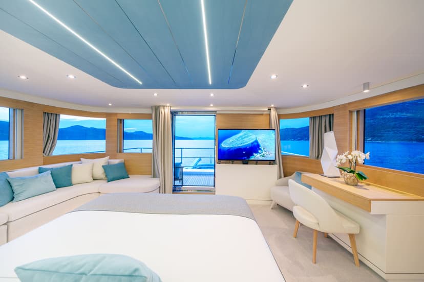 Luxury yacht master cabin with large windows showing ocean and mountains