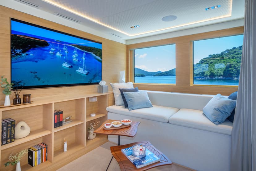 Luxury yacht master saloon interior with sofa, TV, bookshelves, and scenic window views