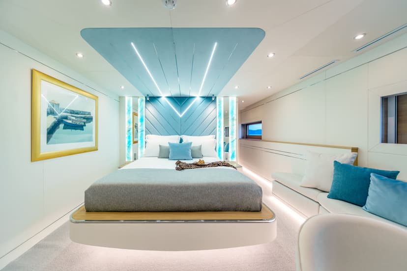 Modern yacht cabin interior with blue accents, lit bed, and wall art