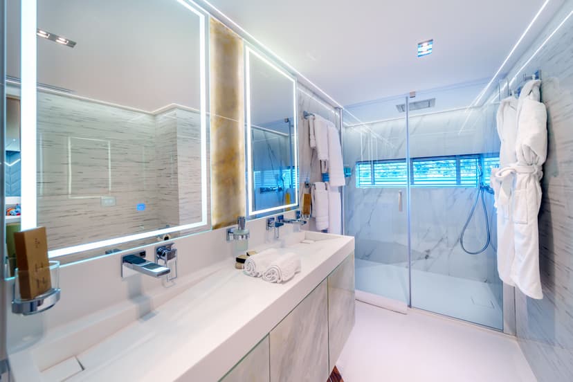 Modern yacht bathroom with double vanity, illuminated mirrors, and glass shower.