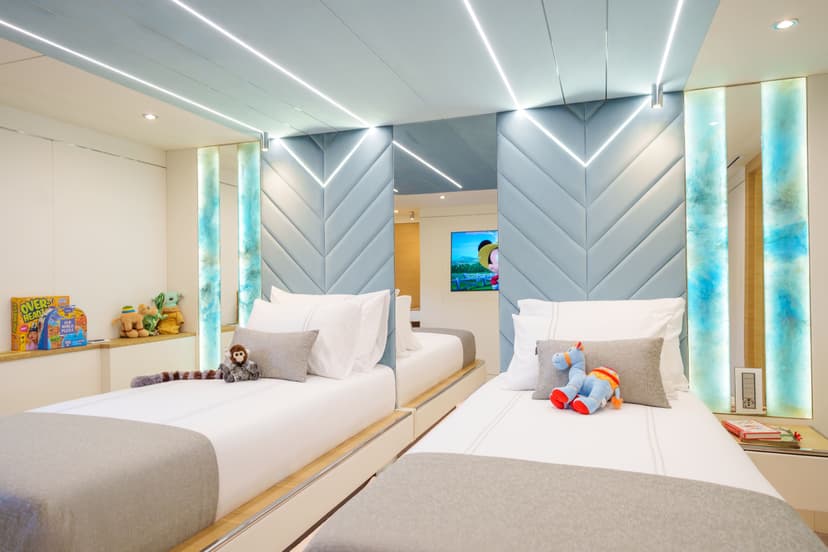 Twin cabin interior with modern blue upholstered headboards and stuffed animals on beds