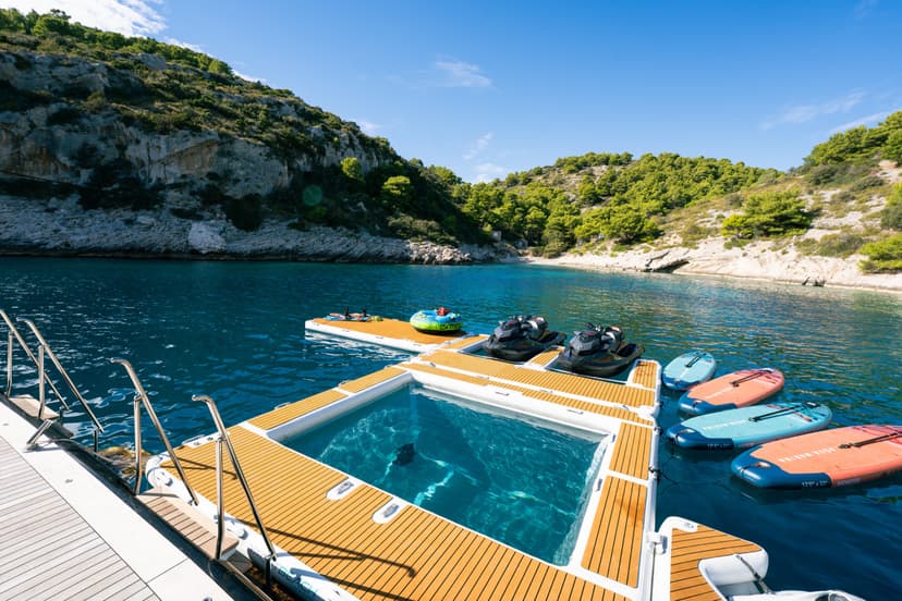 Inflatable floating dock with water pool, jet skis, and paddleboards in coastal bay