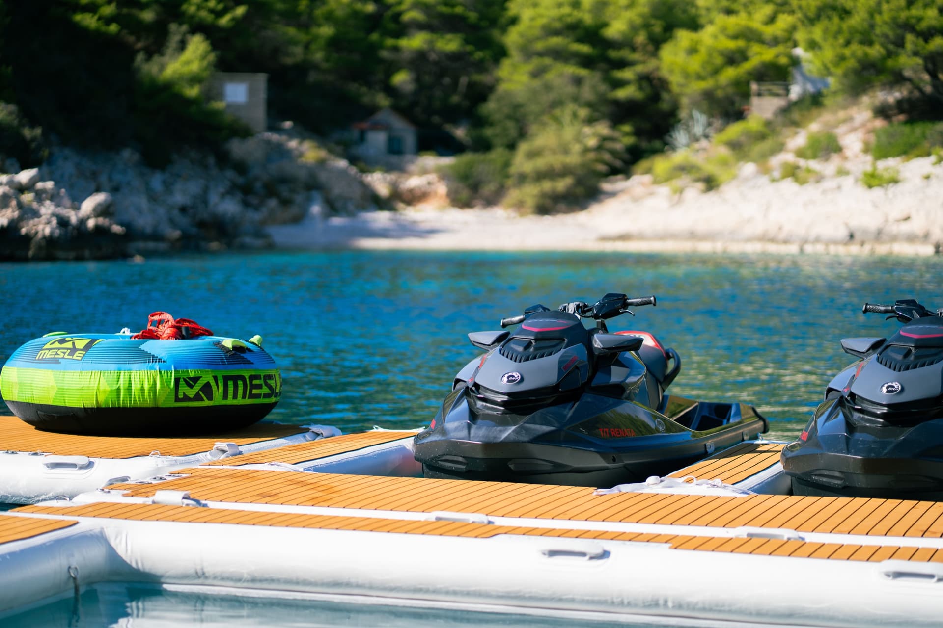 Jet skis and inflatable water tube on floating dock in coastal bay