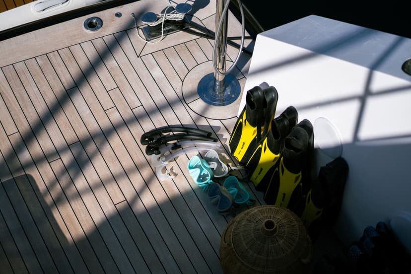 Snorkeling gear including yellow fins and masks on boat deck with wooden planking