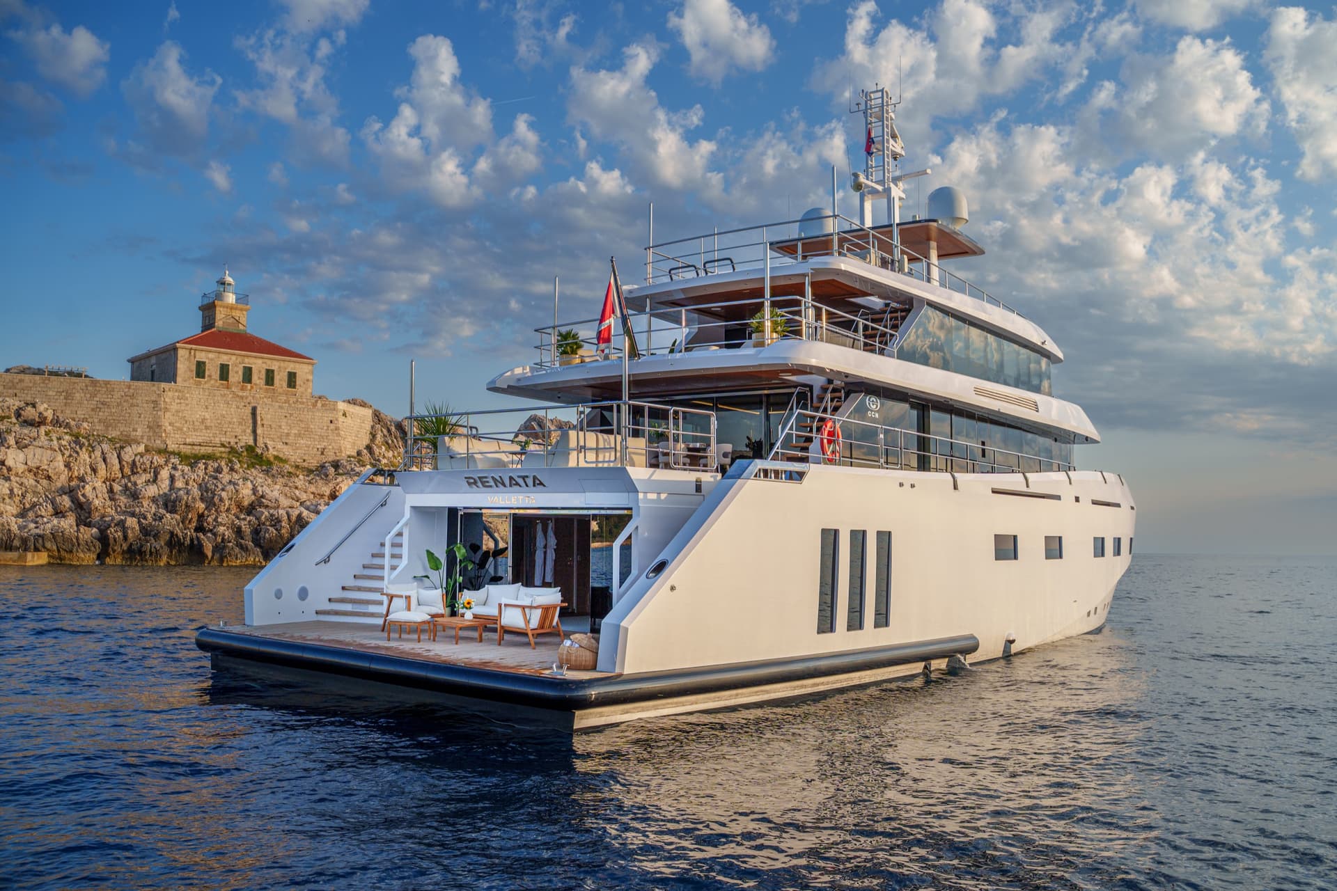 Luxury yacht Renata anchored near a coastal lighthouse on calm sea water
