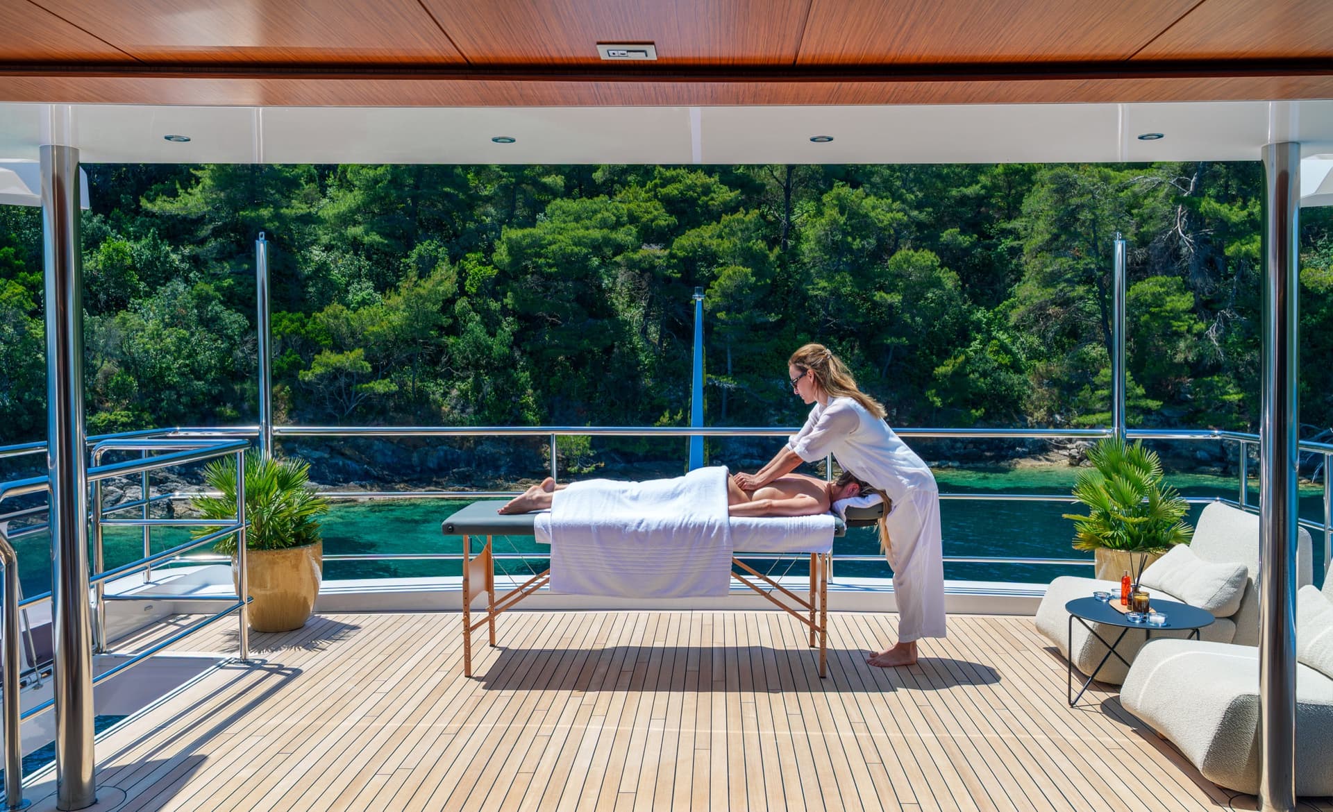 Massage therapist giving a massage on a yacht deck with coastal views