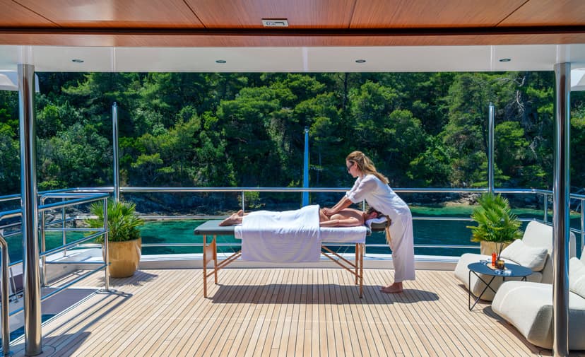 Massage therapist giving a massage on a yacht deck with coastal views